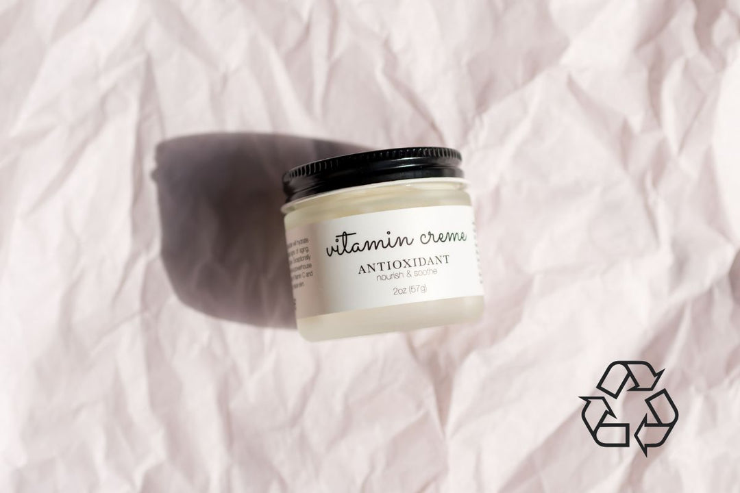 janegee Vitamin Creme jar on textured paper background with soft lighting and a recycling symbol in the corner