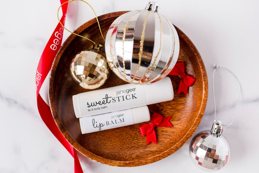 janegee lip balm and sweet stick on a wooden tray with festive ornaments and red ribbon, styled for a holiday setting