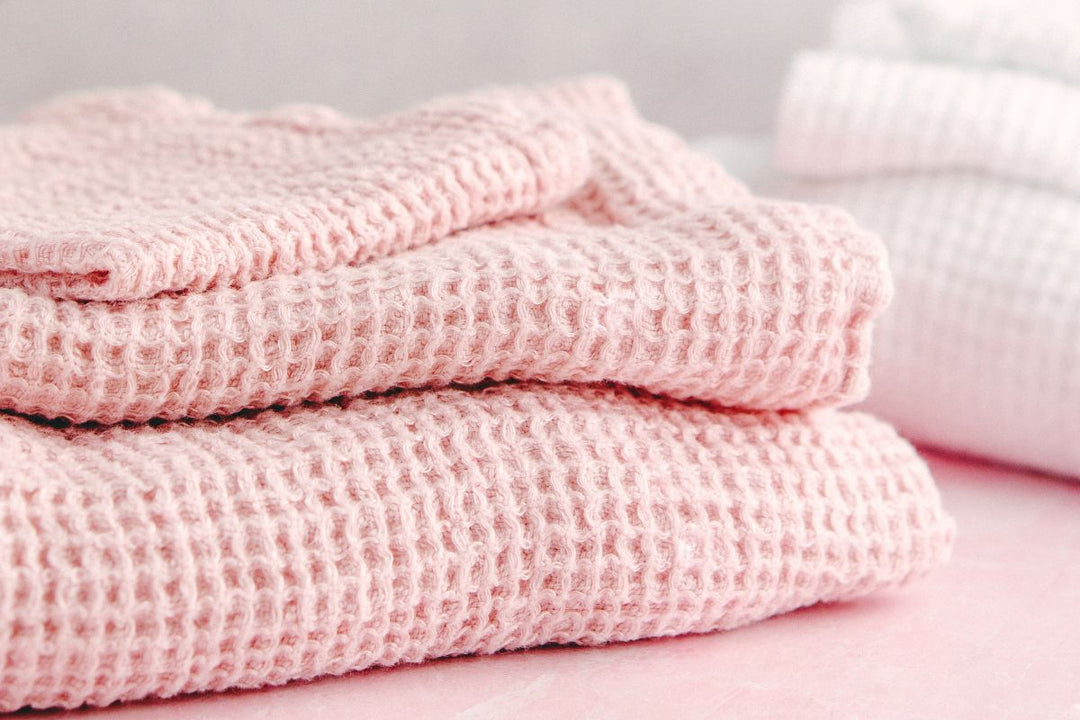 soft pink waffle-knit towels folded neatly, styled in a calm, spa-like setting