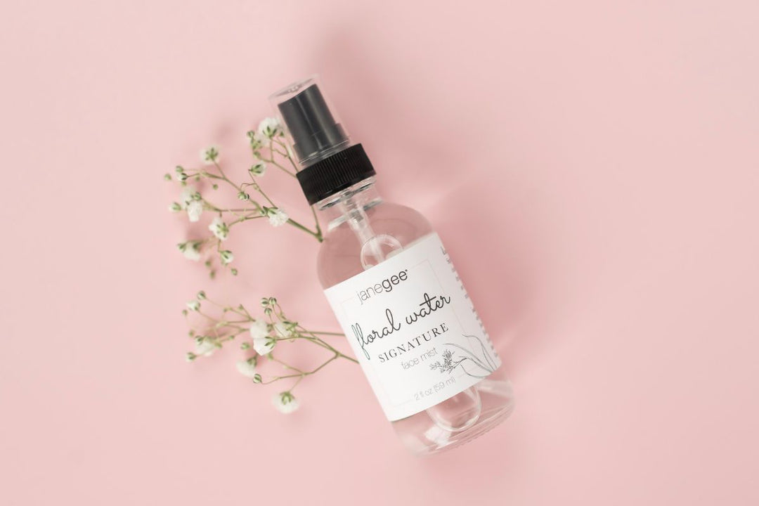 janegee floral water spray bottle styled with delicate white flowers on a soft pink background