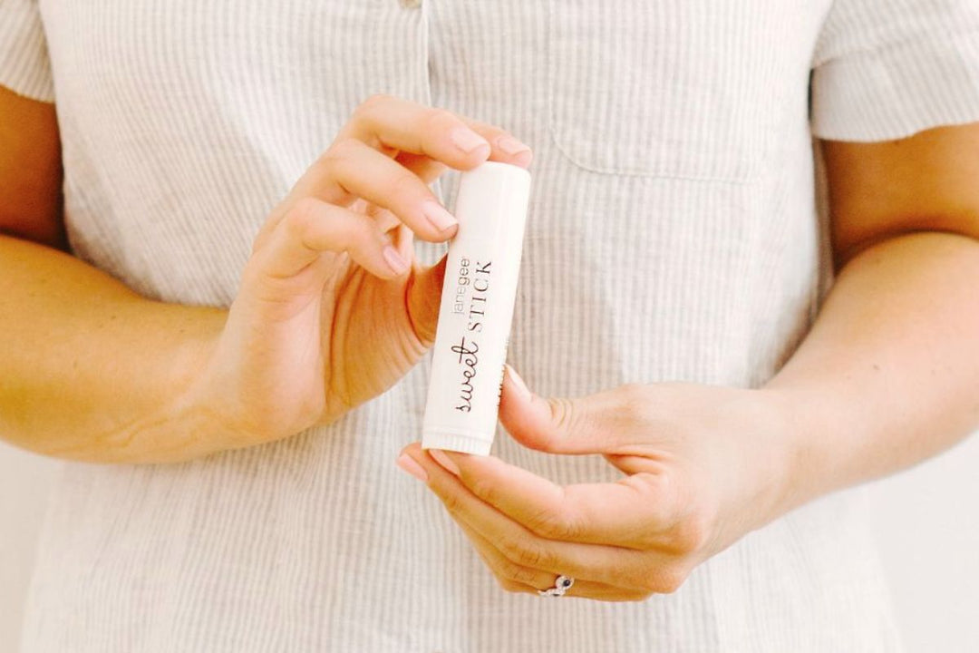hands holding janegee sweet stick lip & body balm, minimal neutral styling with soft natural light