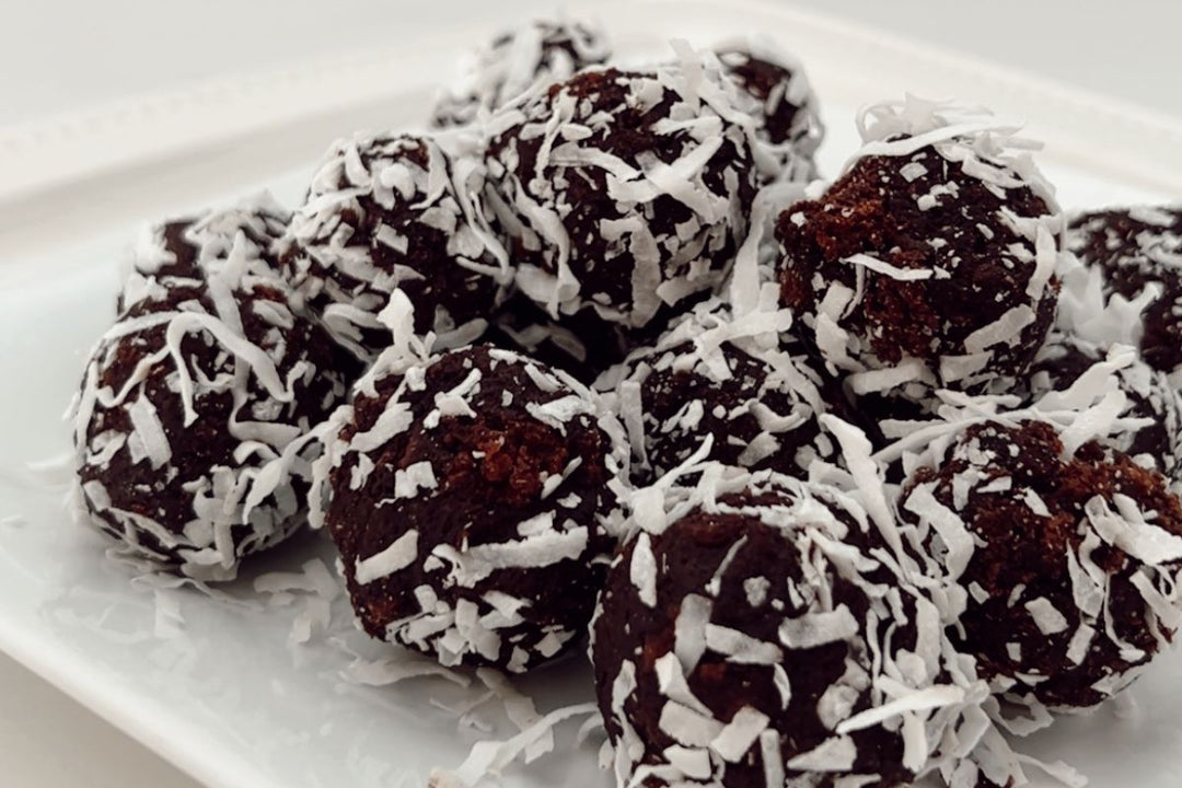 chocolate rum balls coated in shredded coconut, arranged on a white plate