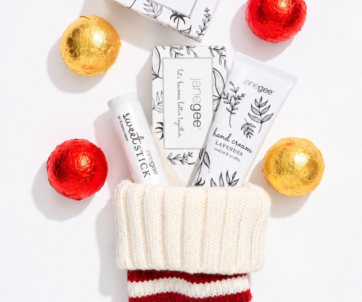 janegee Sweet Stick, gift box, and Lavender Hand Cream tucked into a white and red knit stocking with holiday chocolates.