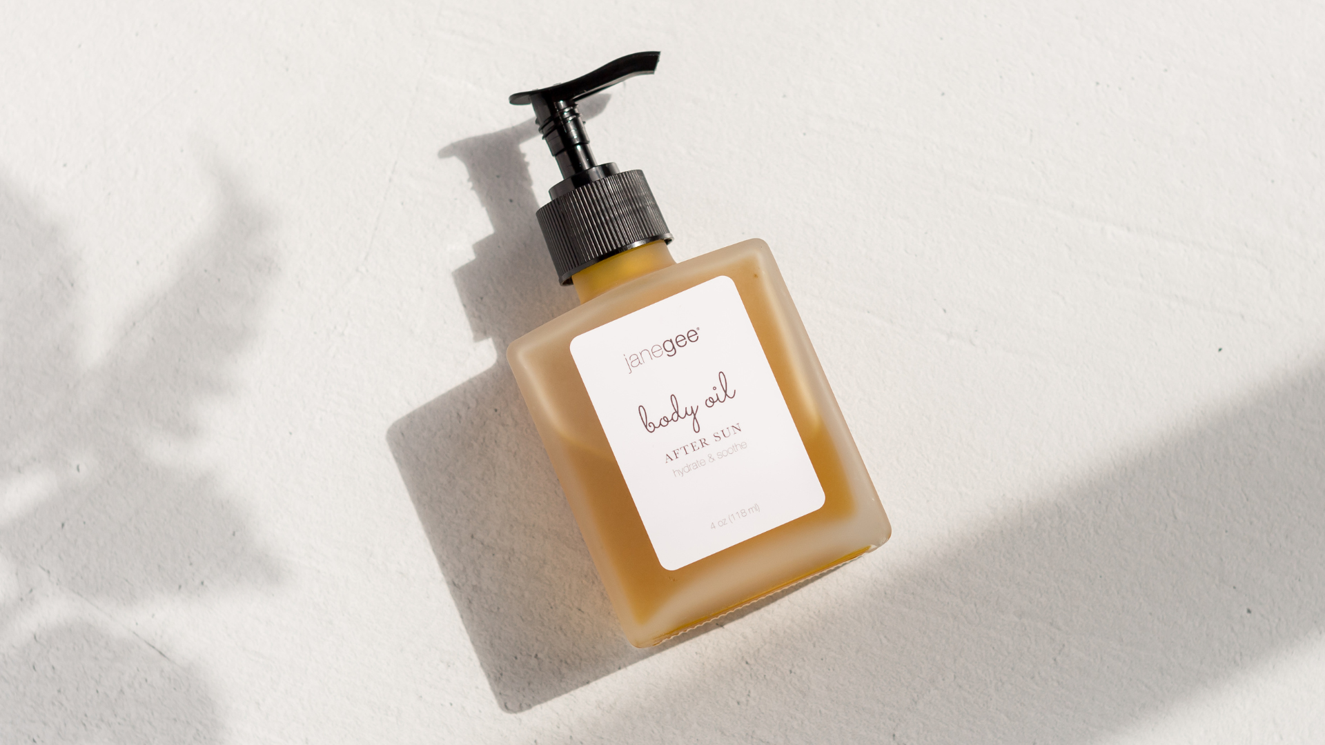 janegee After Sun Body Oil bottle photographed in natural light on textured white background

