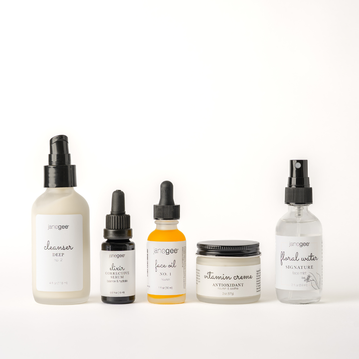 Five janegee skincare products designed for mature skin displayed on a white background, including Cleanser Deep No. 2, Elixir Corrective Serum, Face Oil No. 1, Vitamin Creme Antioxidant Moisturizer, and Signature Floral Water.