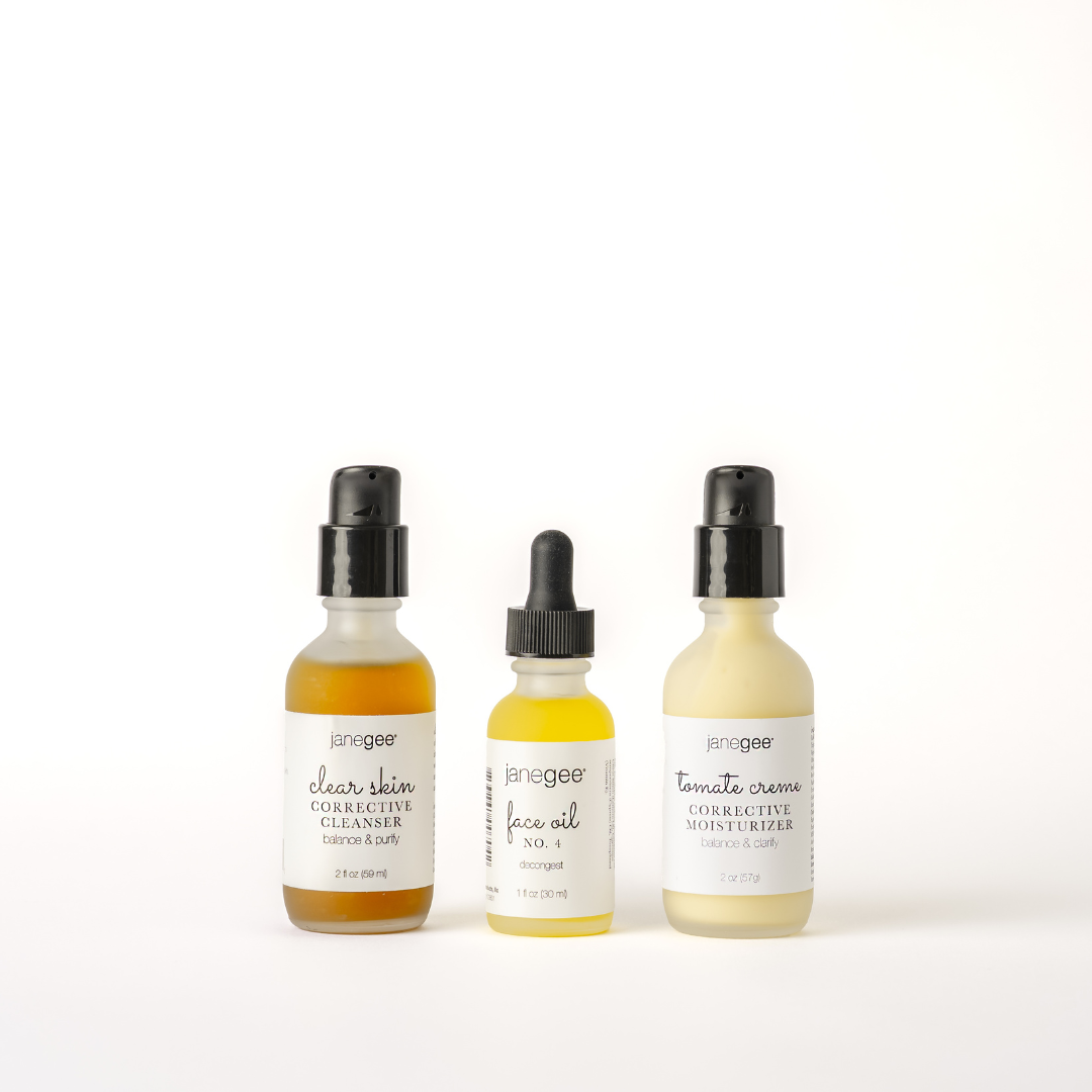Three janegee clear skin essentials arranged on a white background, featuring Clear Skin Corrective Cleanser, Face Oil No. 4, and Tomate Creme Corrective Moisturizer.