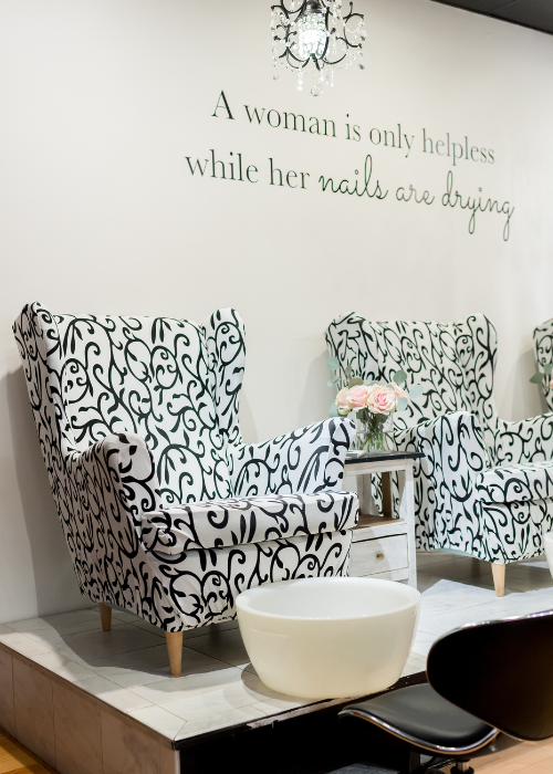 Decorative armchairs with black and white pattern in a room with a wall quote that reads "A woman is only helpless while her nails are drying."