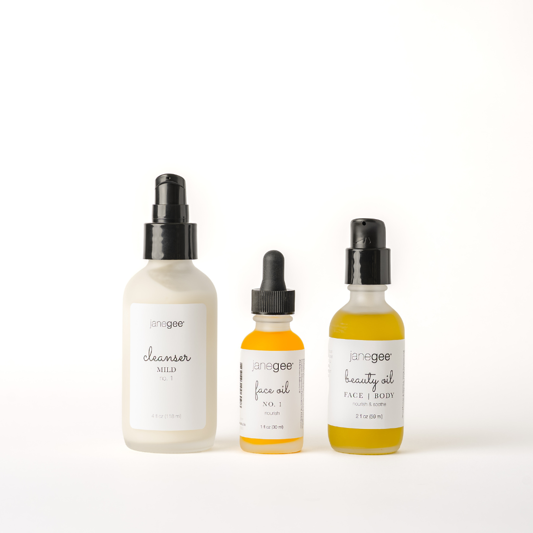 Three janegee skincare essentials on a white background, featuring Cleanser Mild No. 1, Face Oil No. 1, and Beauty Oil in frosted and amber glass bottles.