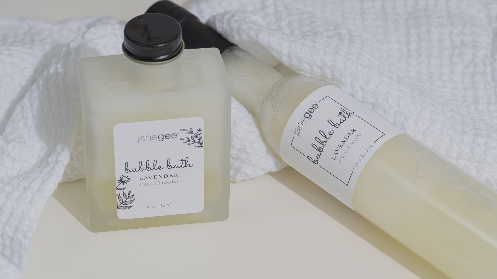 Two bottles of 'janegee' bubble bath on a white towel