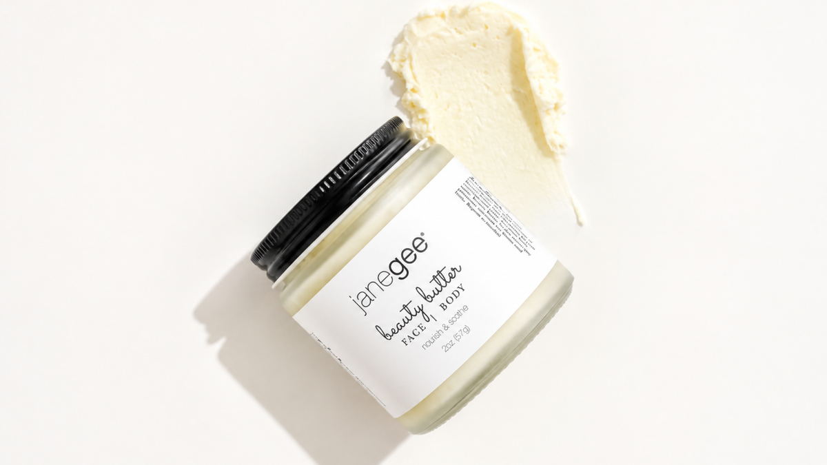Jar of Beauty Butter with product smeared behind the jar showing the contents of the butter