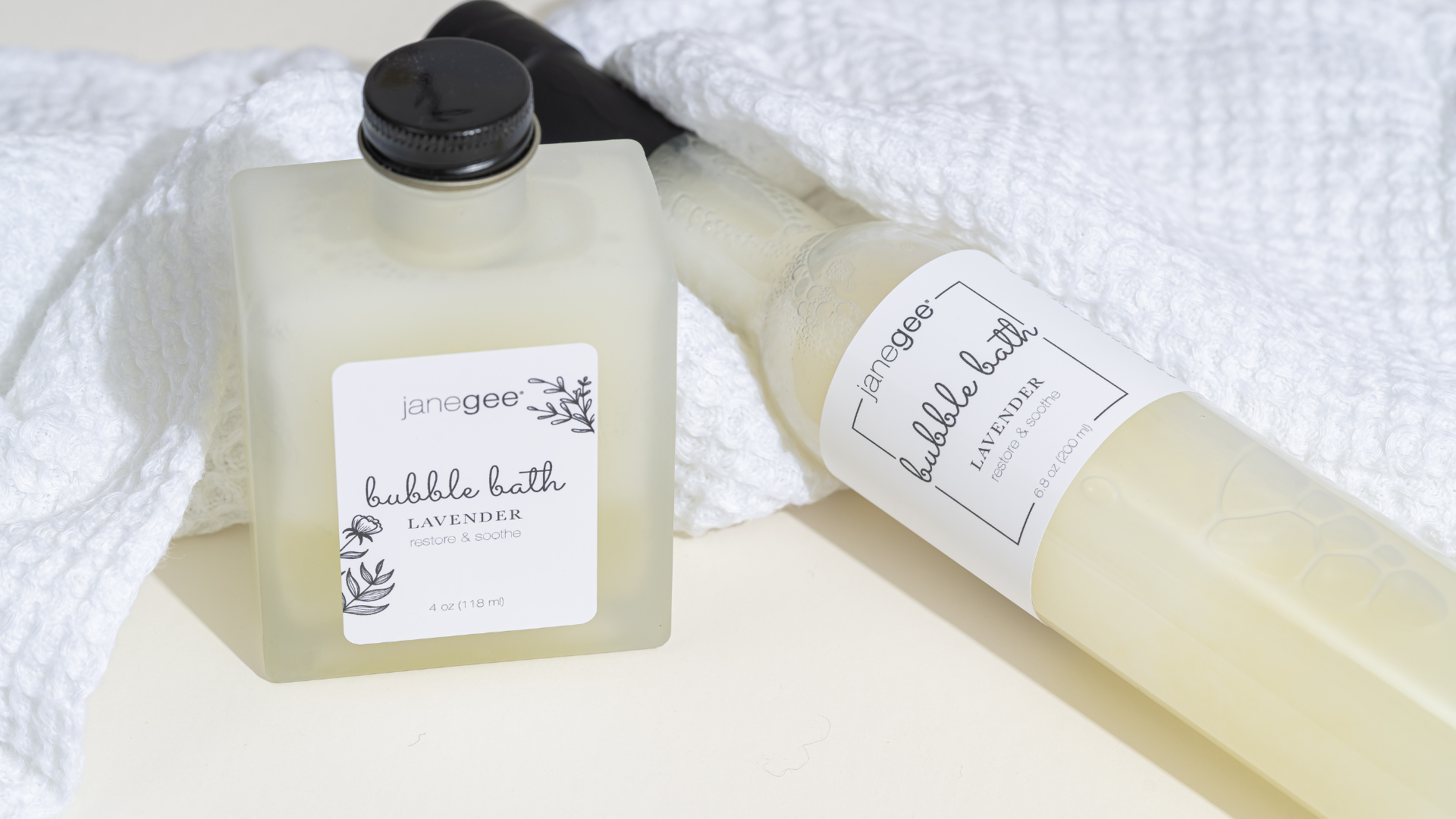 Two bottles of 'janegee' bubble bath on a white towel