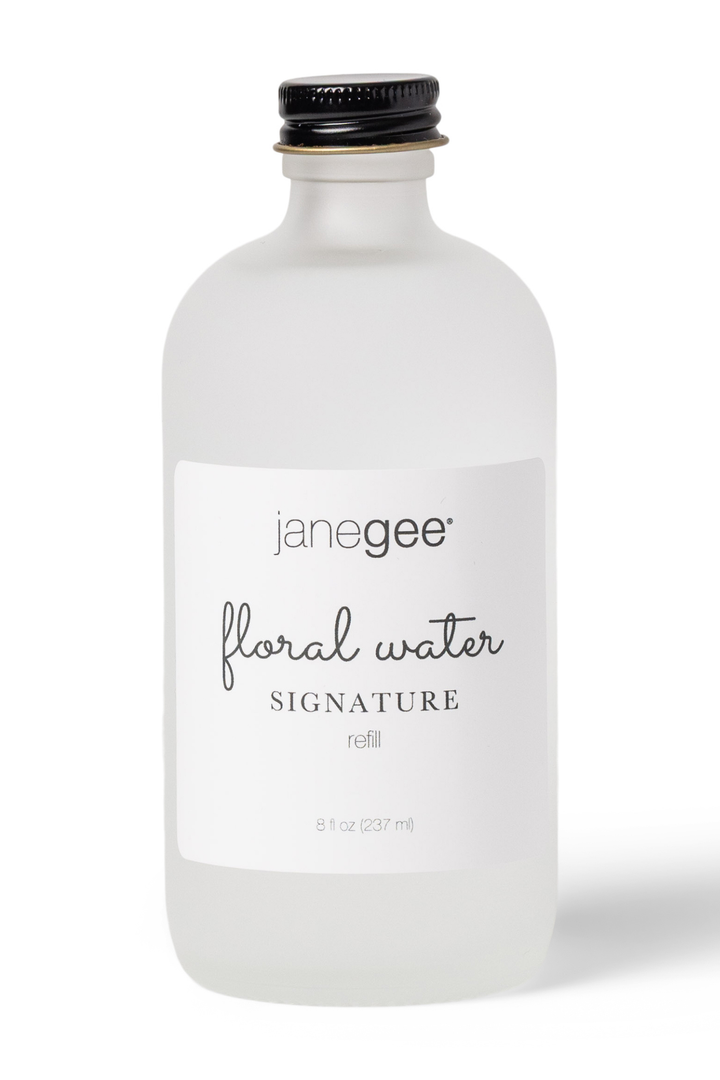 Frosted glass bottle of janegee floral water on a white background