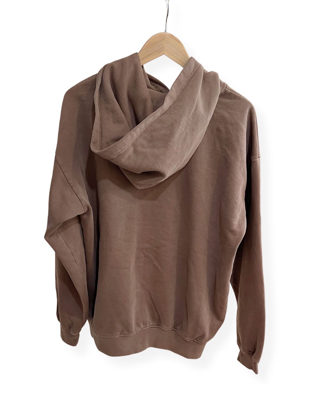 Back view of a brown, oversized fleece janegee hoodie hanging on a wooden hanger, showing a relaxed-fit hood and dropped shoulder seams.