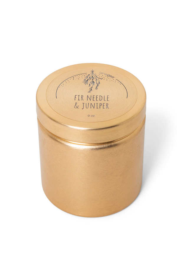 A gold metal candle container with a lid, labeled fir needle and juniper scented candle on a white background.